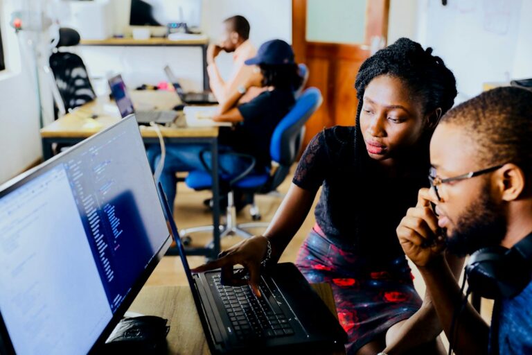 Two software developers reviewing code together on a computer