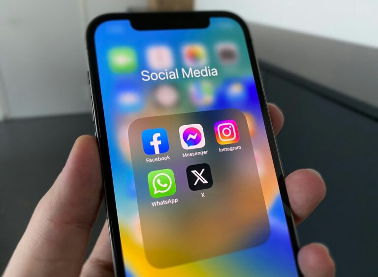 Hand holding a smartphone showing social media apps